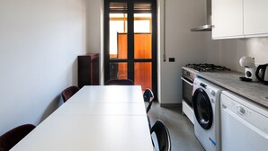 A compact kitchen with a washing machine, a stove, and a dining area with a table and chairs. - Appartamento Matthias by Wonderful Italy (Bari)