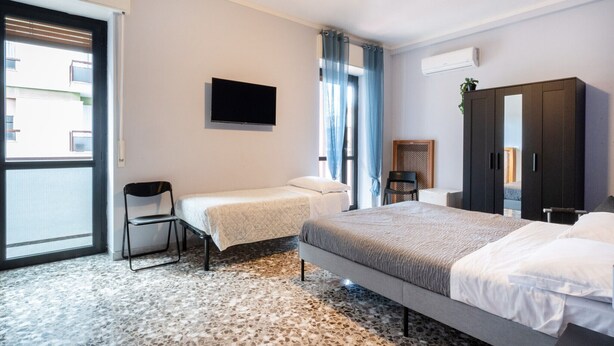 A hotel room with a bed, a chair, a TV, and a wardrobe. - Appartamento Matthias by Wonderful Italy (Bari)