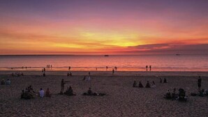 A beach with people relaxing and a sunset in the background. - Darwin Inner City Oasis | 2 Bed Apt (Darwin City)