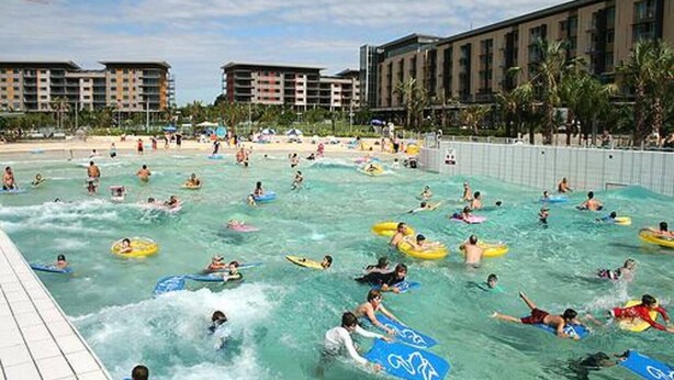A water park with multiple swimming pools, people on water slides, and a large building in the background. - Waterfront Pearl Suite: 2 Bed Luxury Apt by Tropical BNB (Darwin City)