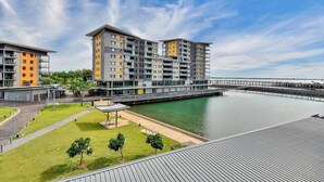 A modern apartment complex with multiple buildings, a waterfront view, and a pedestrian bridge. - Waterfront Pearl Suite: 2 Bed Luxury Apt by Tropical BNB (Darwin City)