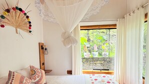 A bed with a floral bedspread, a decorative fan, and a wooden ceiling. - www.ecoterralodge.com (Santa Teresa)