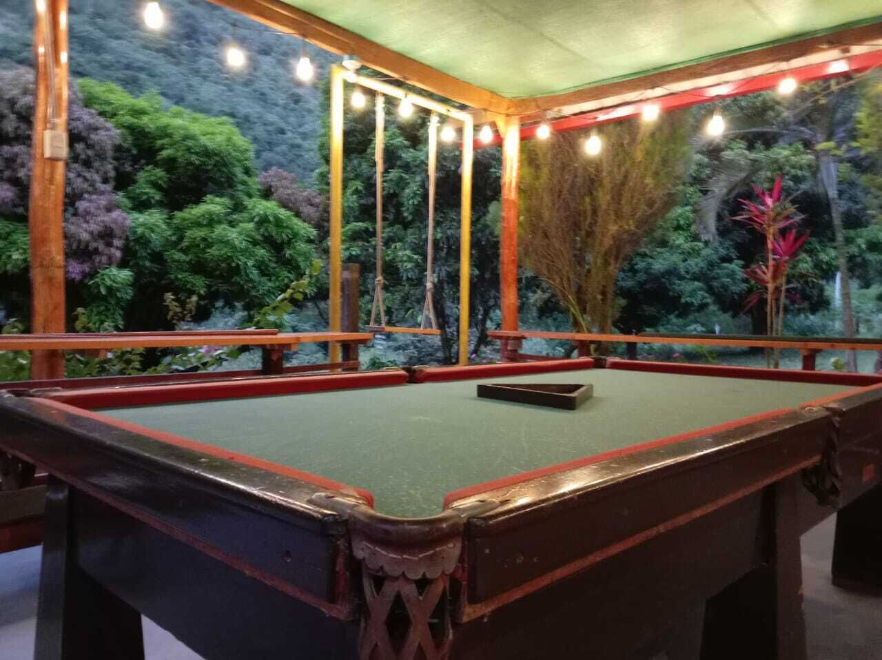 Une table de billard dans une pièce dont le tapis est vert, entourée d’un cadre en bois et d’une bordure rouge.