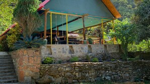 A building with a green roof and a stone wall in front. - www.ecoterralodge.com (Santa Teresa)