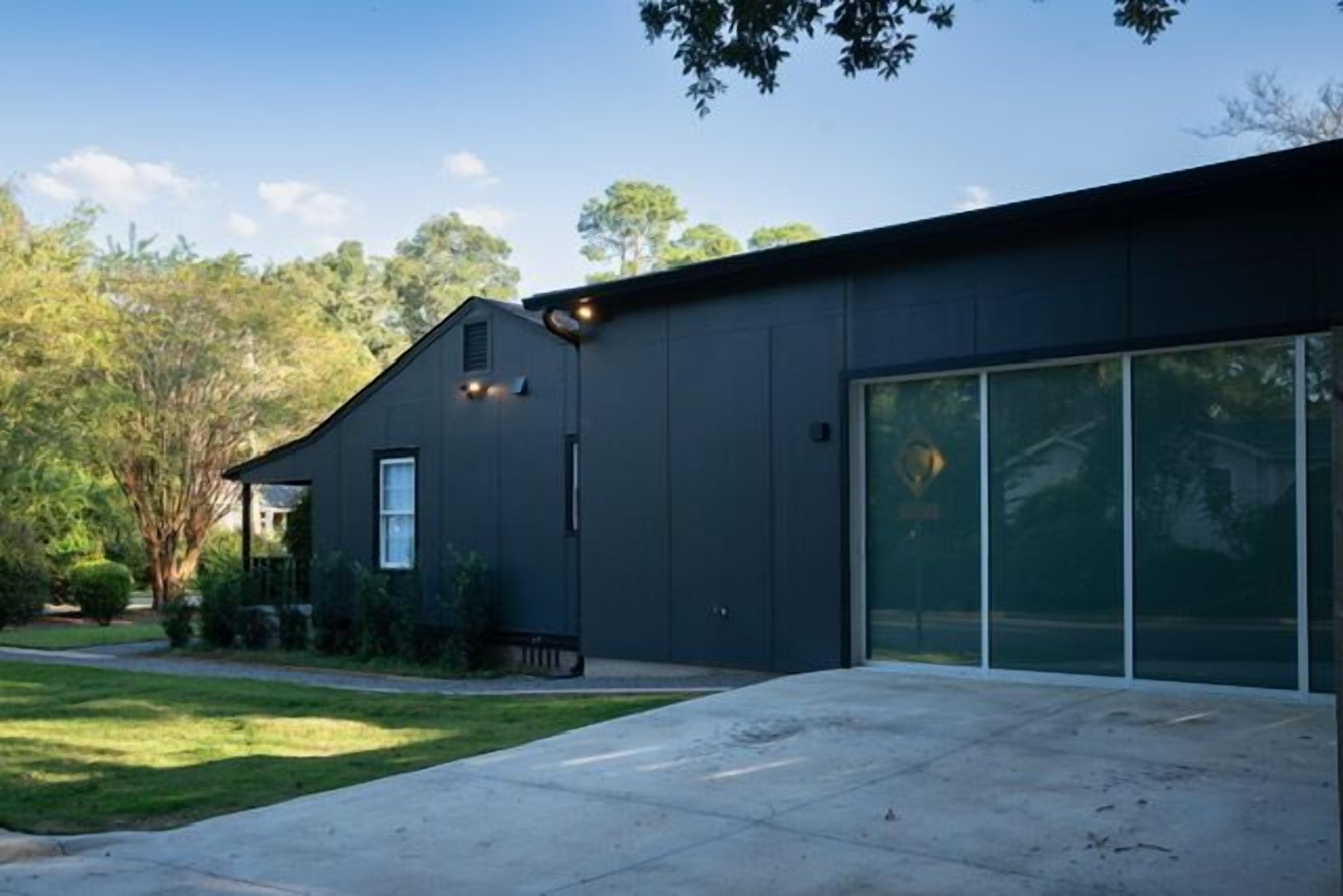 A modern building with a dark exterior, large windows, and a well-maintained lawn.