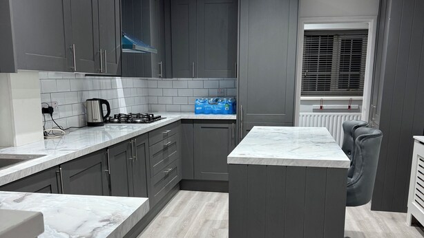 A modern kitchen with grey cabinets, a marble countertop, and a central island.