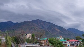 A mountainous landscape with residential buildings in the foreground. - Kailasham Stay (Dharamshala)