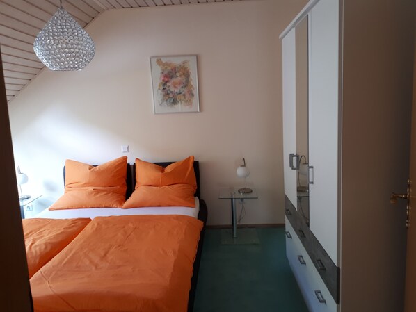 A bedroom with a bed, a bedside table, a lamp, a wardrobe, and a ceiling light.
