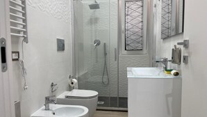 A modern bathroom with a glass-enclosed shower, a white sink, and a toilet. - Greta family house: Clare (Roma)