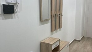 A hotel room with a wooden wardrobe, a bedside table, and a wall-mounted mirror. - Greta family house: Clare (Roma)