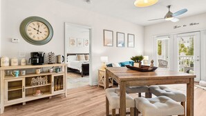 Un salon chaleureux avec une table basse en bois, une table à manger avec des chaises, une horloge murale et un ventilateur de plafond.
