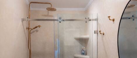 Une salle de bain moderne dotée d’une douche à parois de verre, d’un pommeau de douche à main et d’un robinet mural.