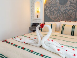 A bed with a decorative swan towel arrangement and a wall with a geometric pattern. - Riad Medina d'Or (Marrakech)