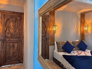A bedroom with a large mirror, wooden doors, and a bed with patterned pillows. - Riad Medina d'Or (Marrakech)