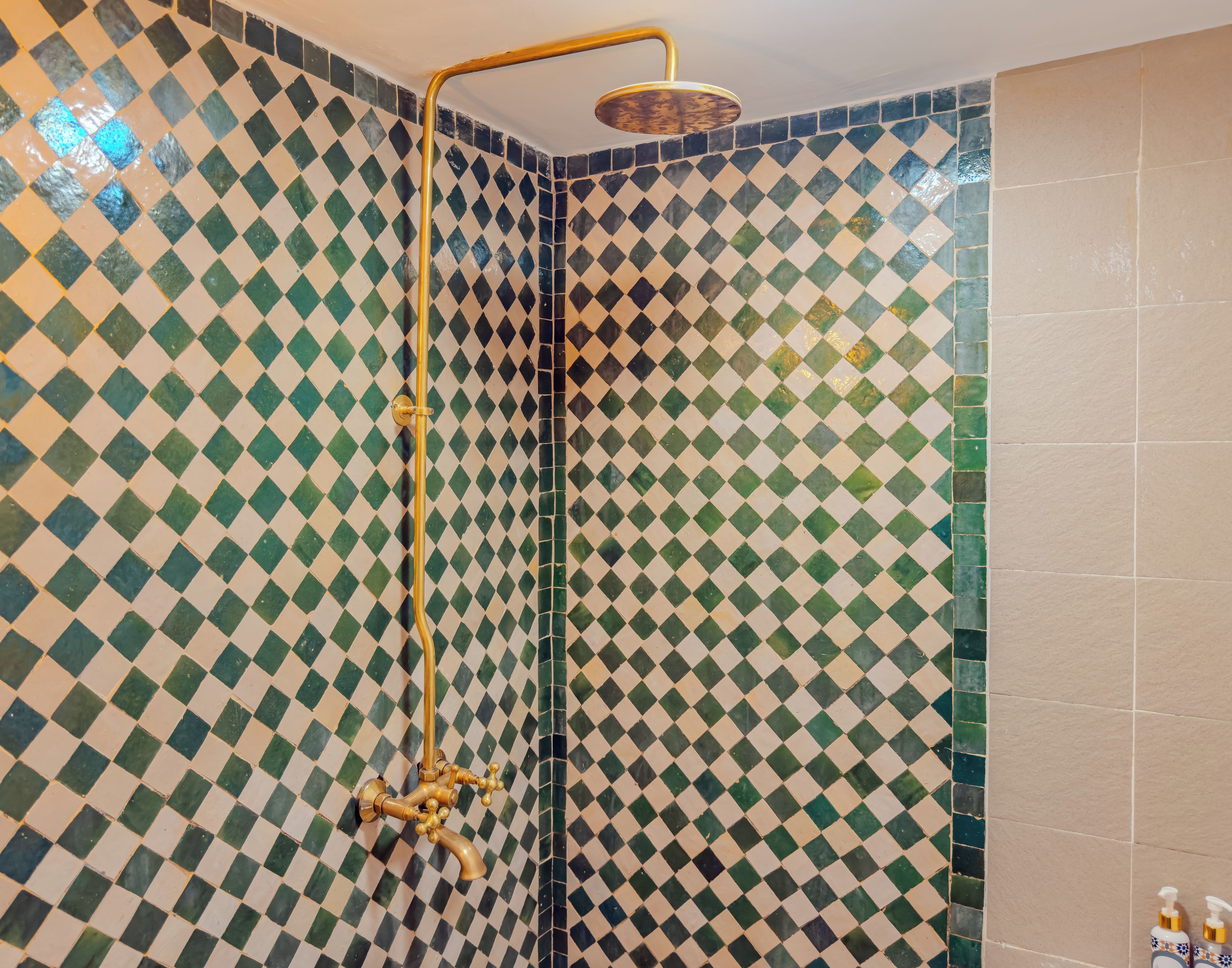 A shower with a gold faucet and a checkered tile pattern on the walls.