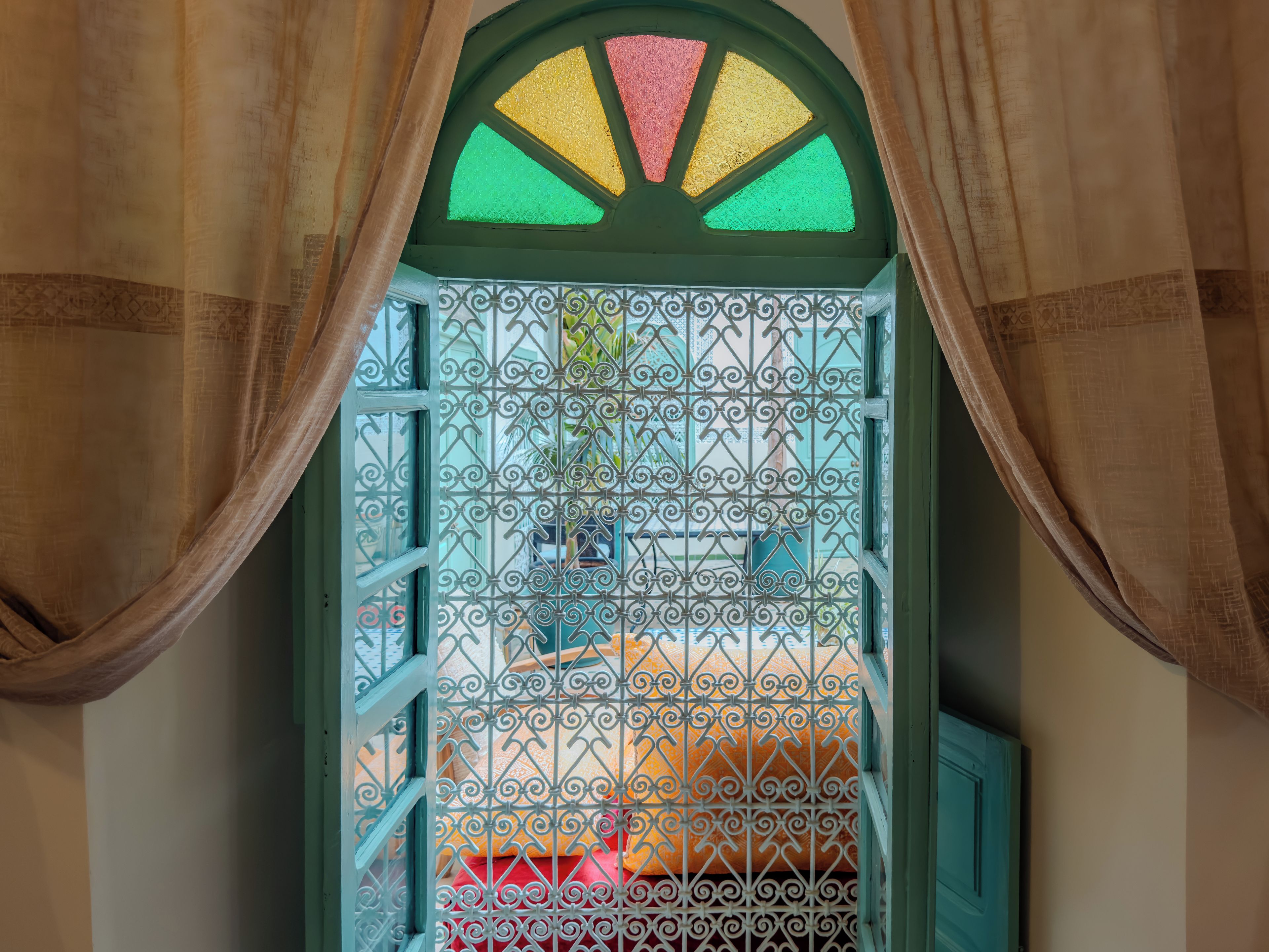 A window with a decorative metal grille and curtains.