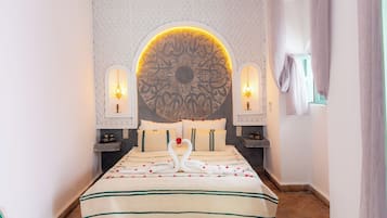 Habitación de hotel con un amplio panel decorativo, una cama con colcha floral y dos lámparas de pared.