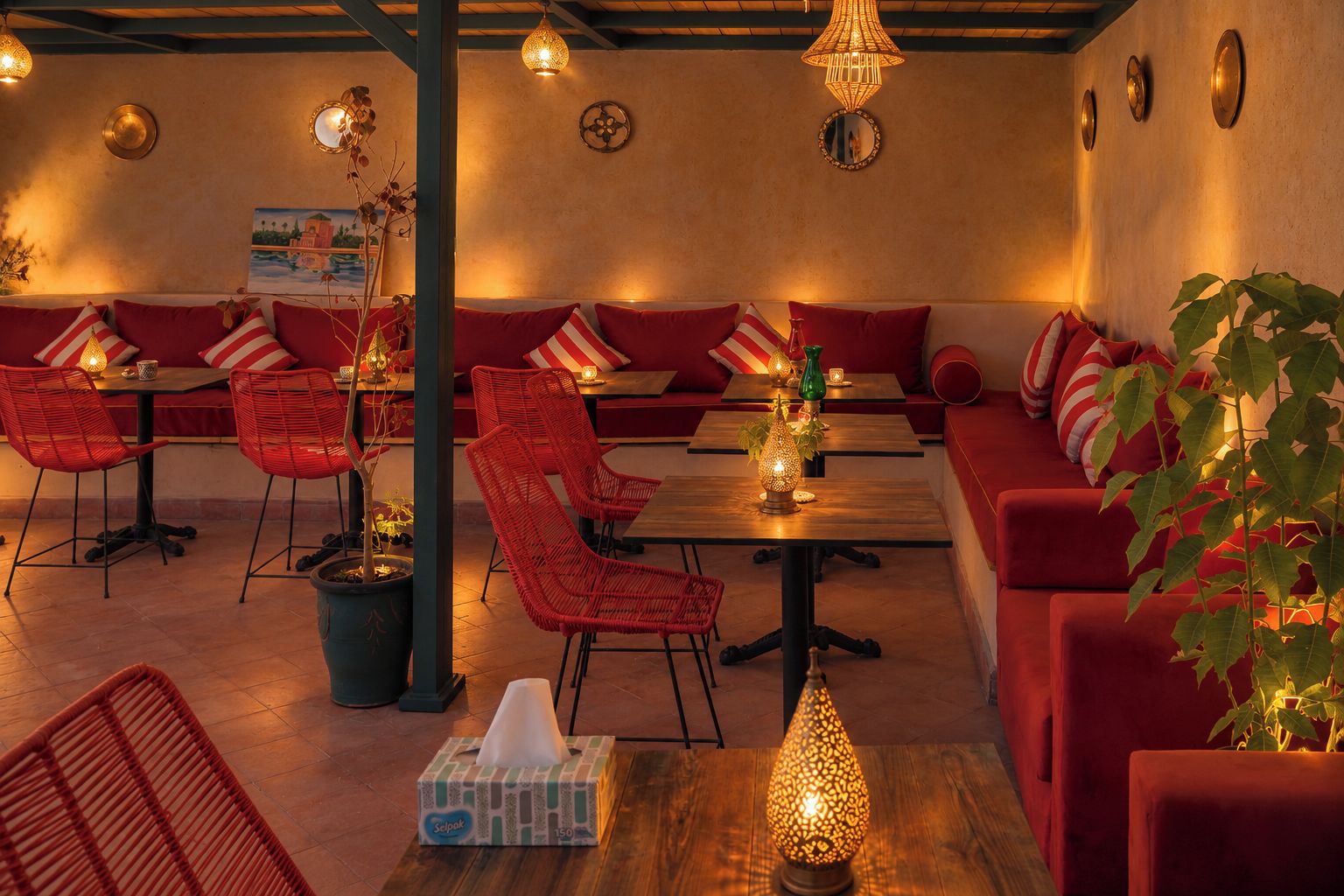 A restaurant with red upholstered seating, wicker chairs, and tables with candles.