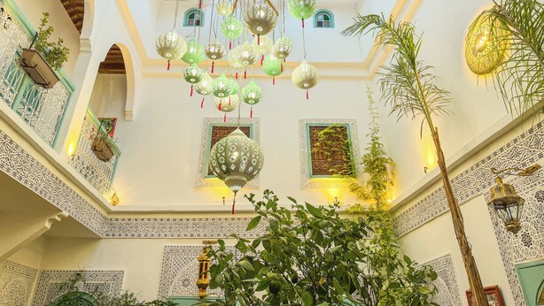 Een ruime atrium met een hoge plafond, versierde lantaarns en gedetailleerde wanddecoraties.
