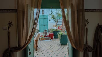 A view through a doorway into a room with a tiled floor, a green door, and potted plants.
