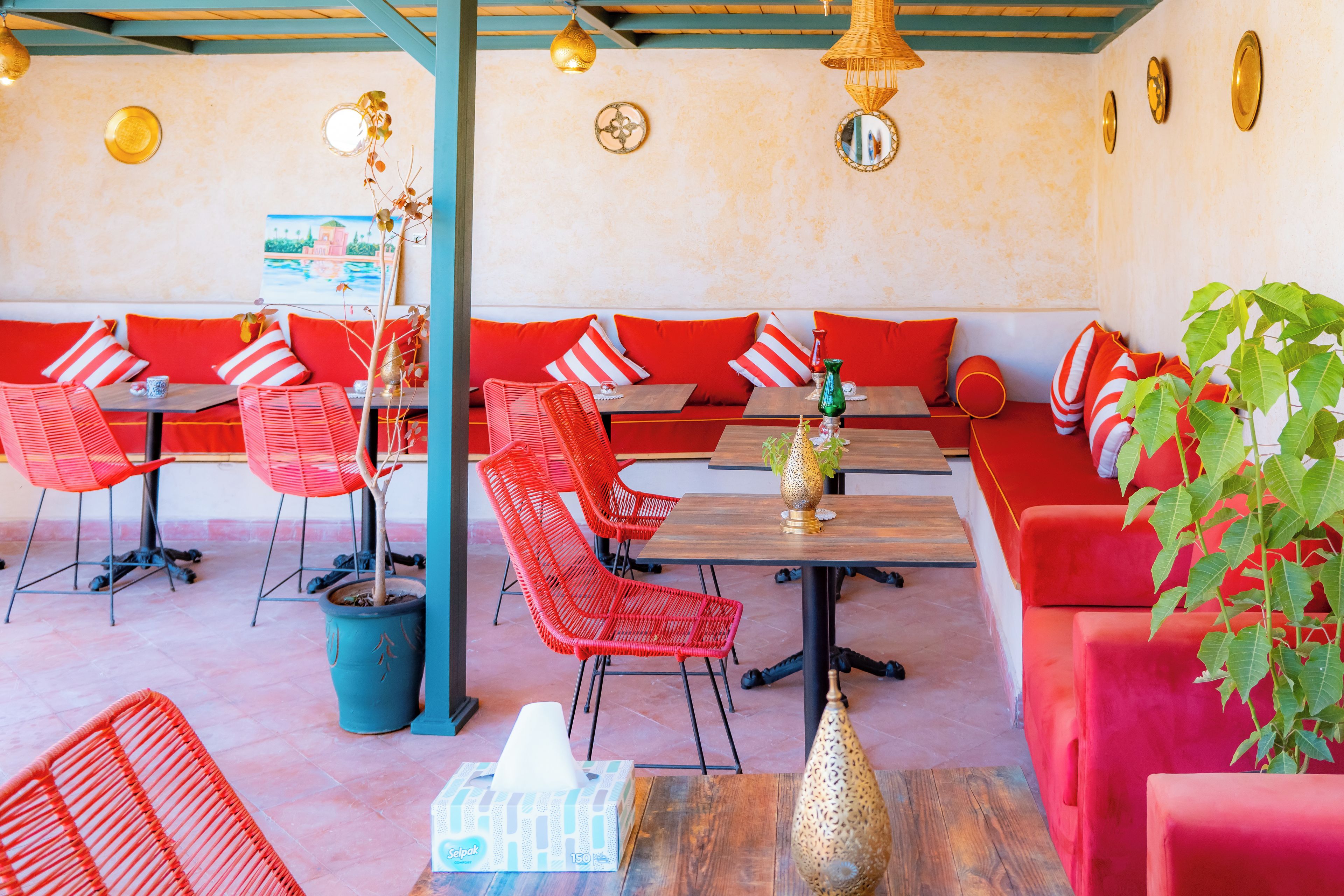 A restaurant interior with red and white striped cushions, wicker chairs, and a wooden table.