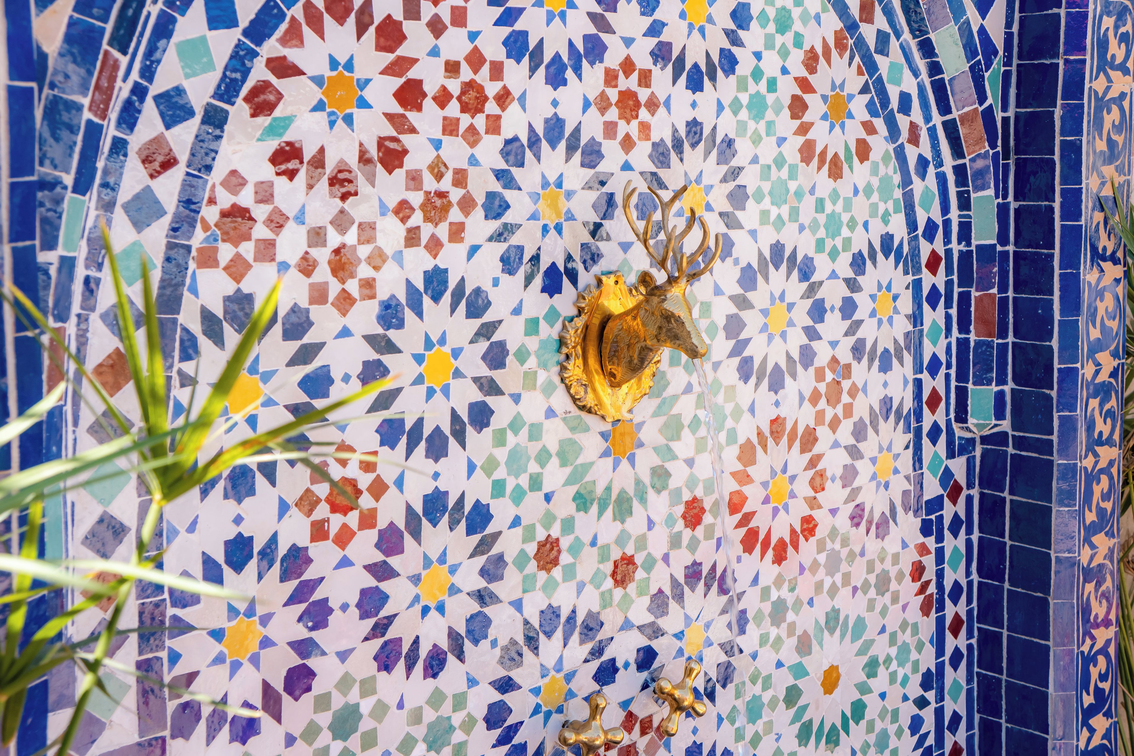 Un mur décoré d’une mosaïque représentant une tête de cerf et ses bois.