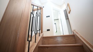 A wooden staircase with a metal railing leading to a room with a white wall and a framed picture. - Charming London House - Sleeps 4 & Outdoor Space (London)
