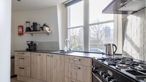 Une cuisine moderne avec des meubles en bois, une cuisinière en acier inoxydable et une fenêtre donnant sur l’extérieur.