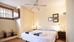 A bedroom with a bed, bedside tables, a ceiling fan, a window, and two potted plants. - Villa Sol in J vea With 2 Bedrooms and 2 Bathrooms (Javea)