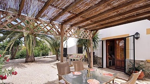 An outdoor patio with a glass table, wicker chairs, and a pergola. - Villa Sol in J vea With 2 Bedrooms and 2 Bathrooms (Javea)