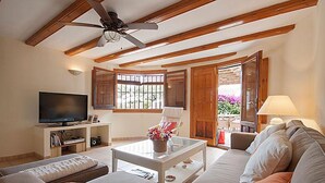 A living room with a sofa, a coffee table, a TV, and a ceiling fan. - Villa Sol in J vea With 2 Bedrooms and 2 Bathrooms (Javea)