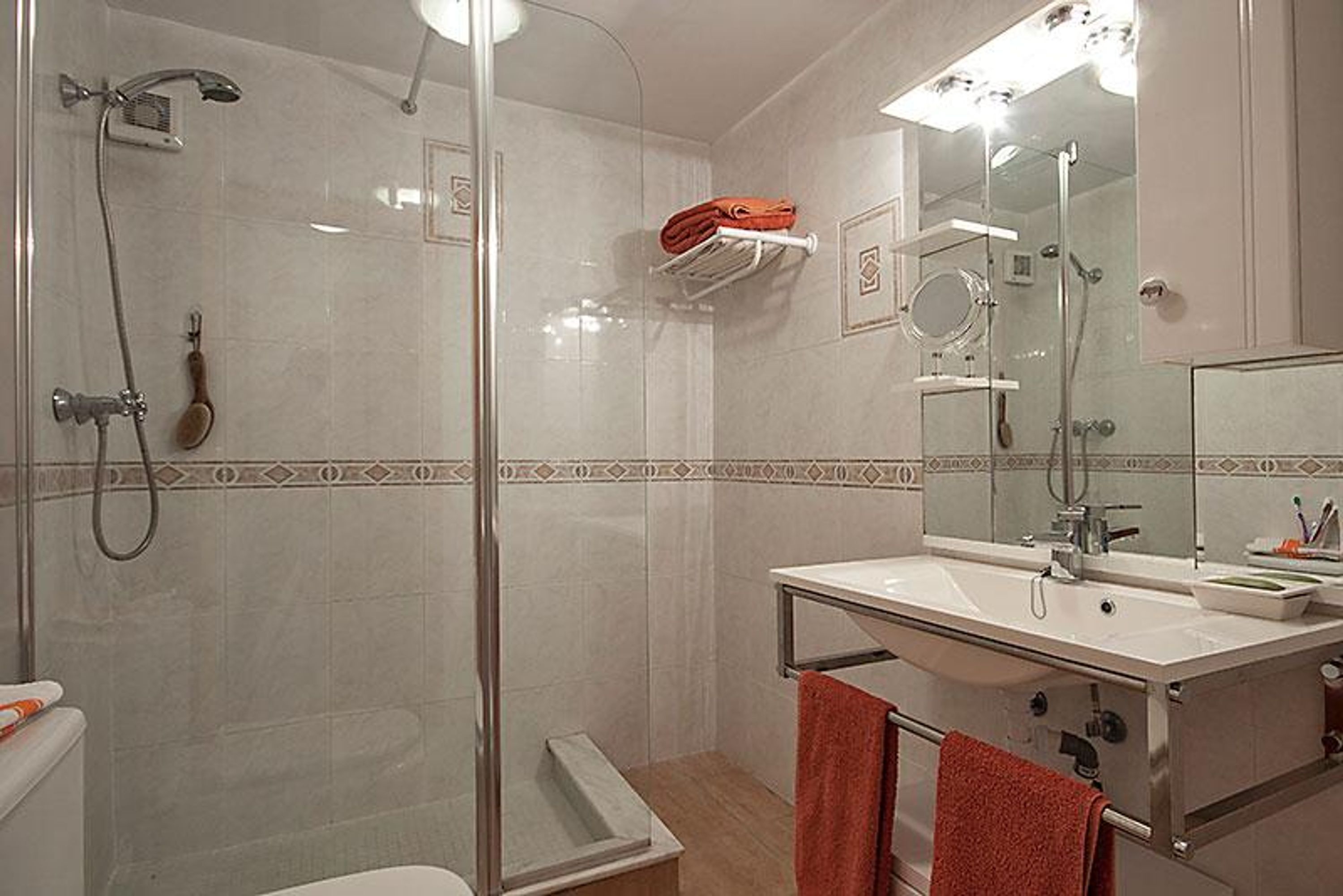 Une salle de bain moderne avec une douche à parois de verre, un lavabo blanc avec un miroir et un porte-serviettes.