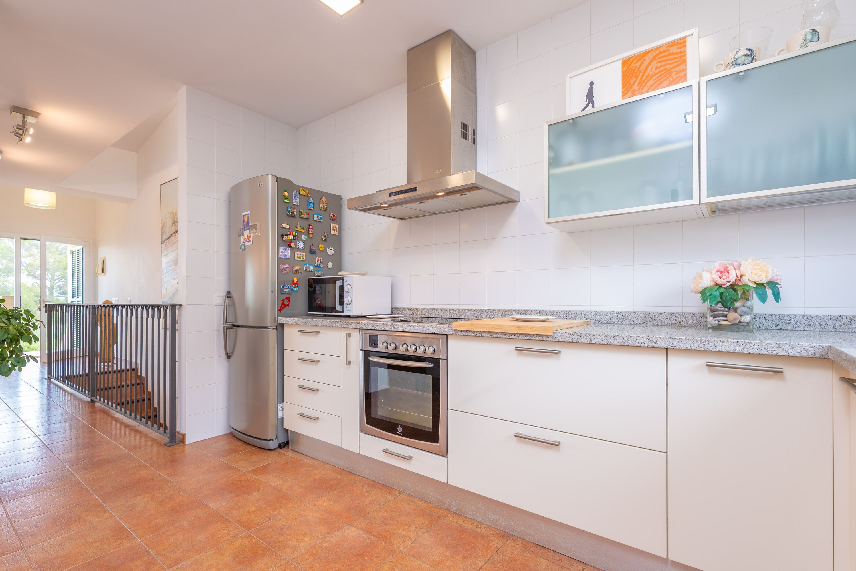 Una cocina moderna con armarios blancos, electrodomésticos de acero inoxidable y salpicadero de azulejos.