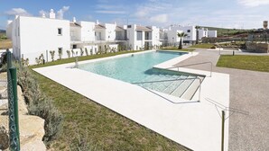 En modern vit byggnad med en swimmingpool och en klarblå himmel.
