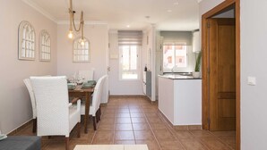 A dining area with a table, chairs, and a hanging light fixture. - Novo Golf Chiclana in Chiclana de la Frontera (Chiclana de la Frontera)