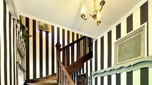 Eine Holztreppe mit schwarz-weiß gestreiften Wänden, einem Kronleuchter und einem gemusterten Boden.