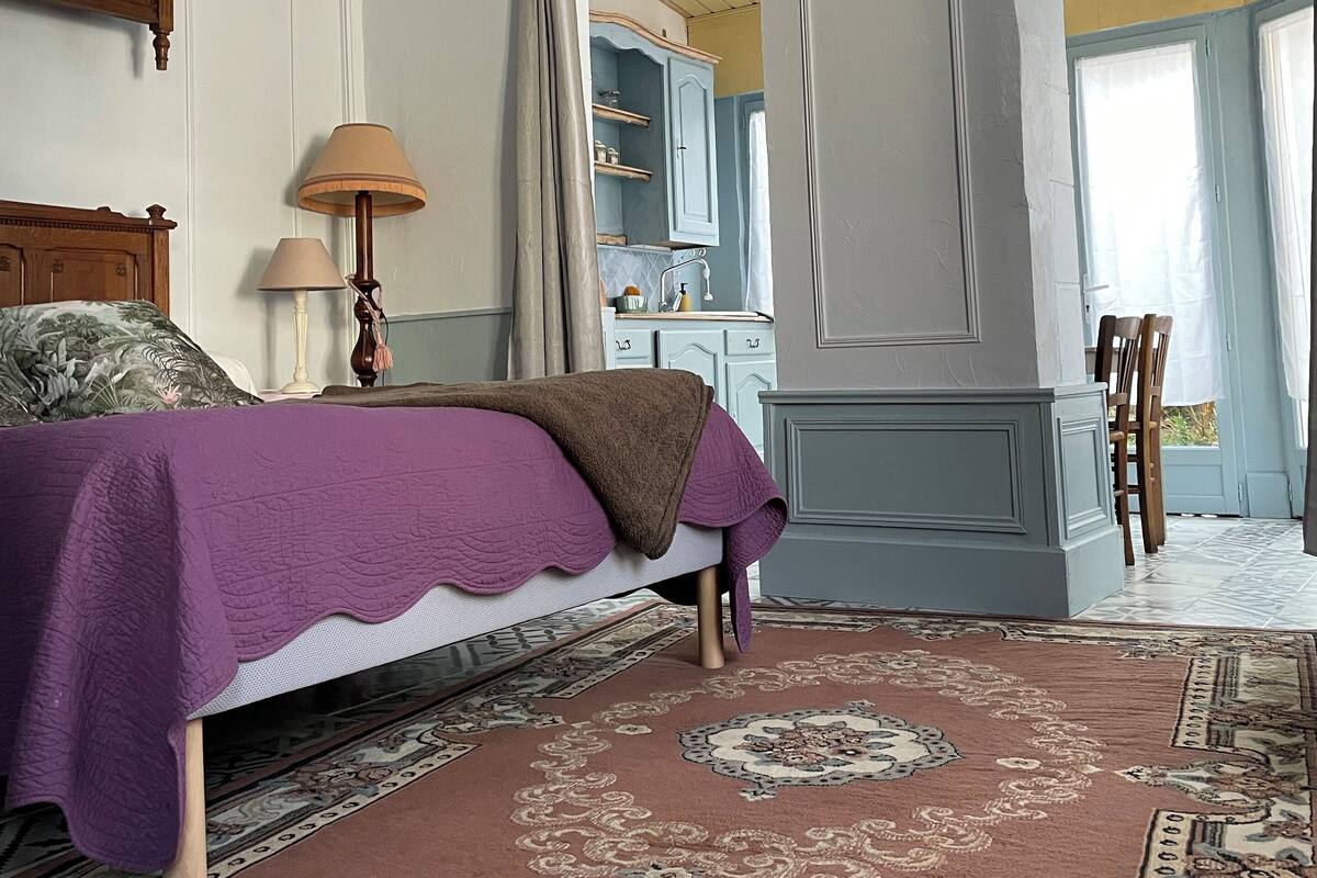 A bedroom with a bed, a nightstand, a lamp, and a view into the bathroom.