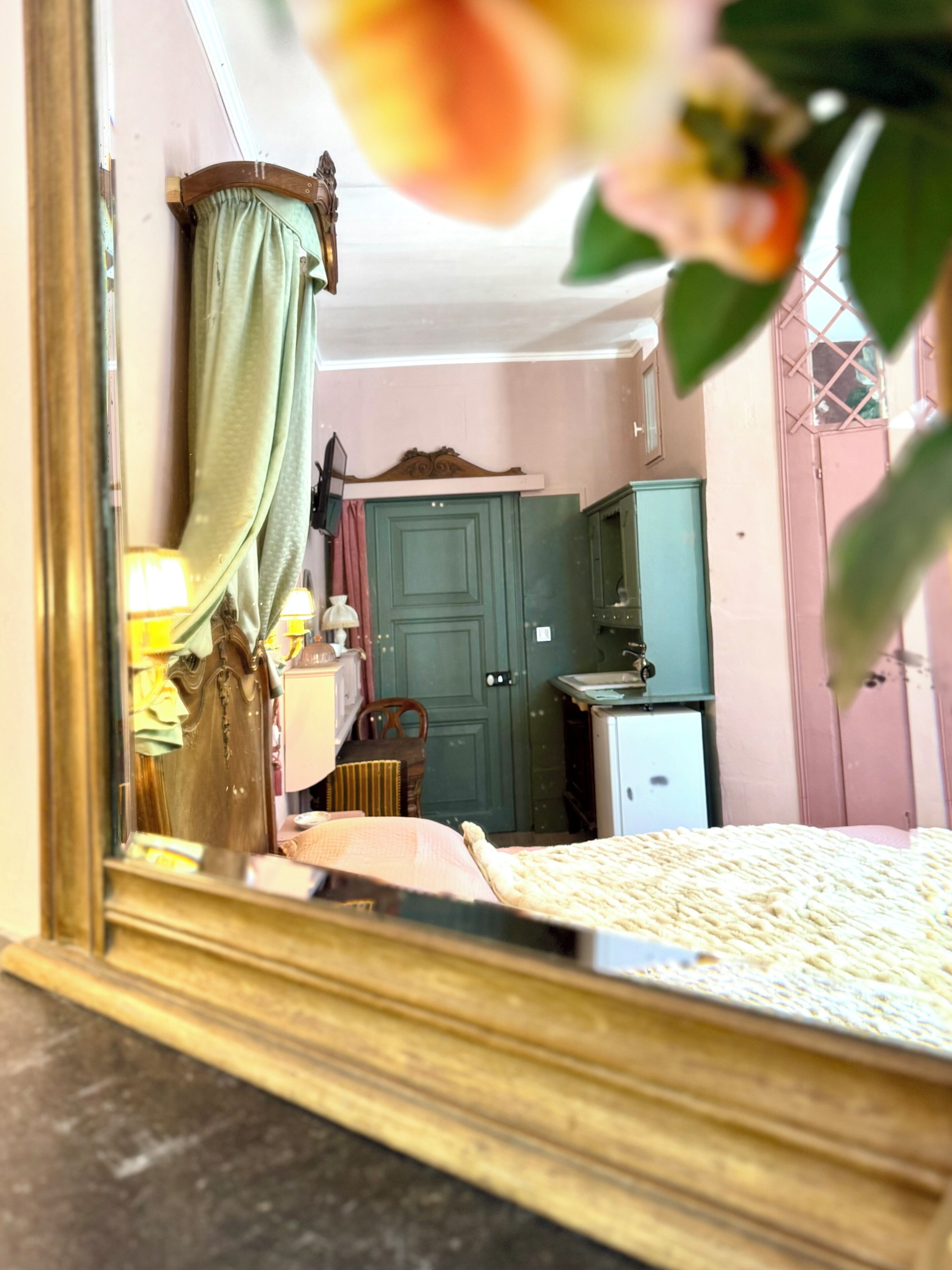 Quarto com cama, guarda-roupa, escrivaninha e espelho refletindo o ambiente.