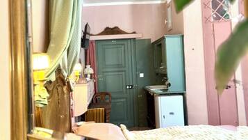 Quarto com cama, guarda-roupa, escrivaninha e espelho refletindo o ambiente.