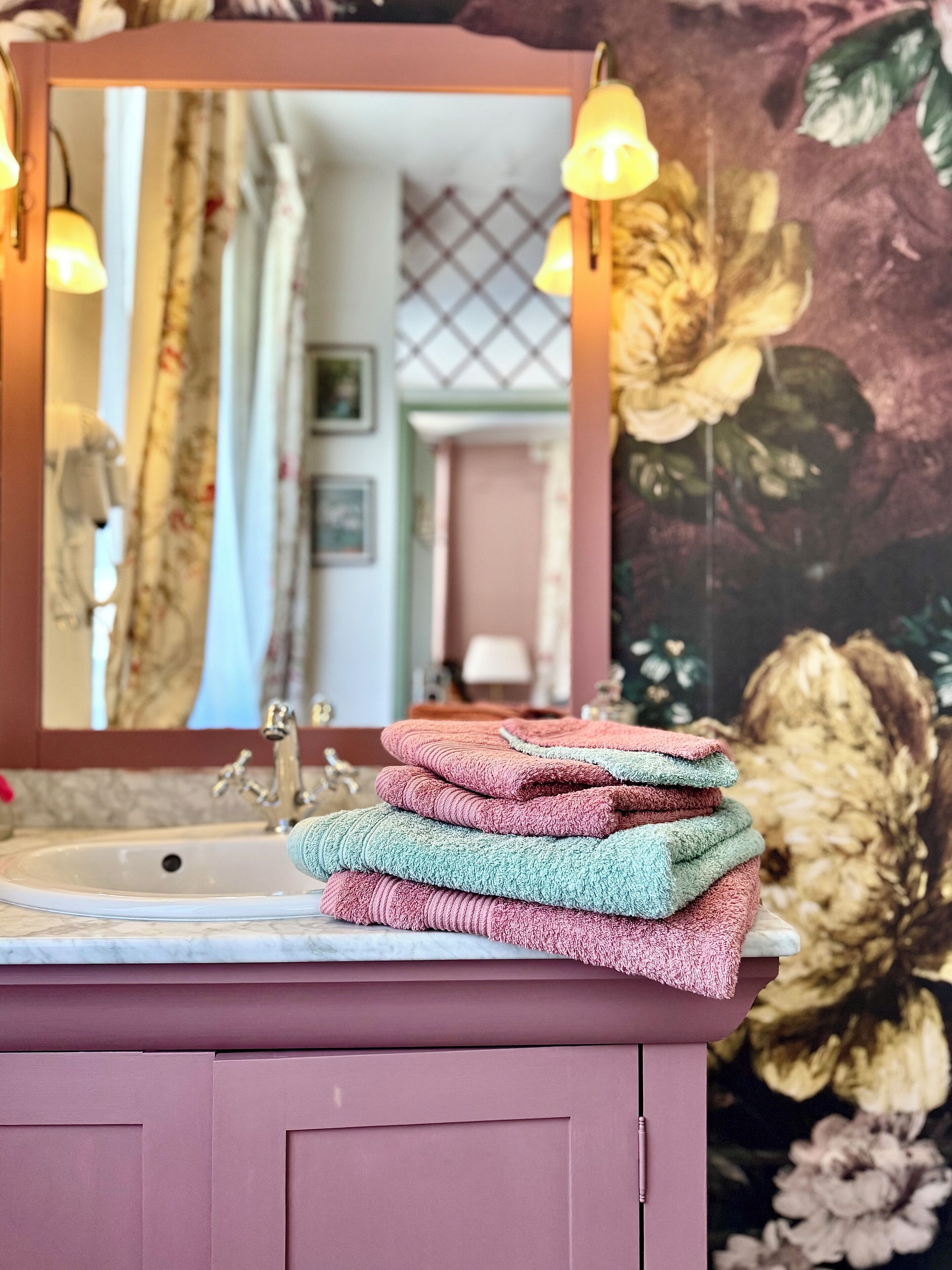 A bathroom with a sink, mirror, and decorative towels stacked on a vanity.