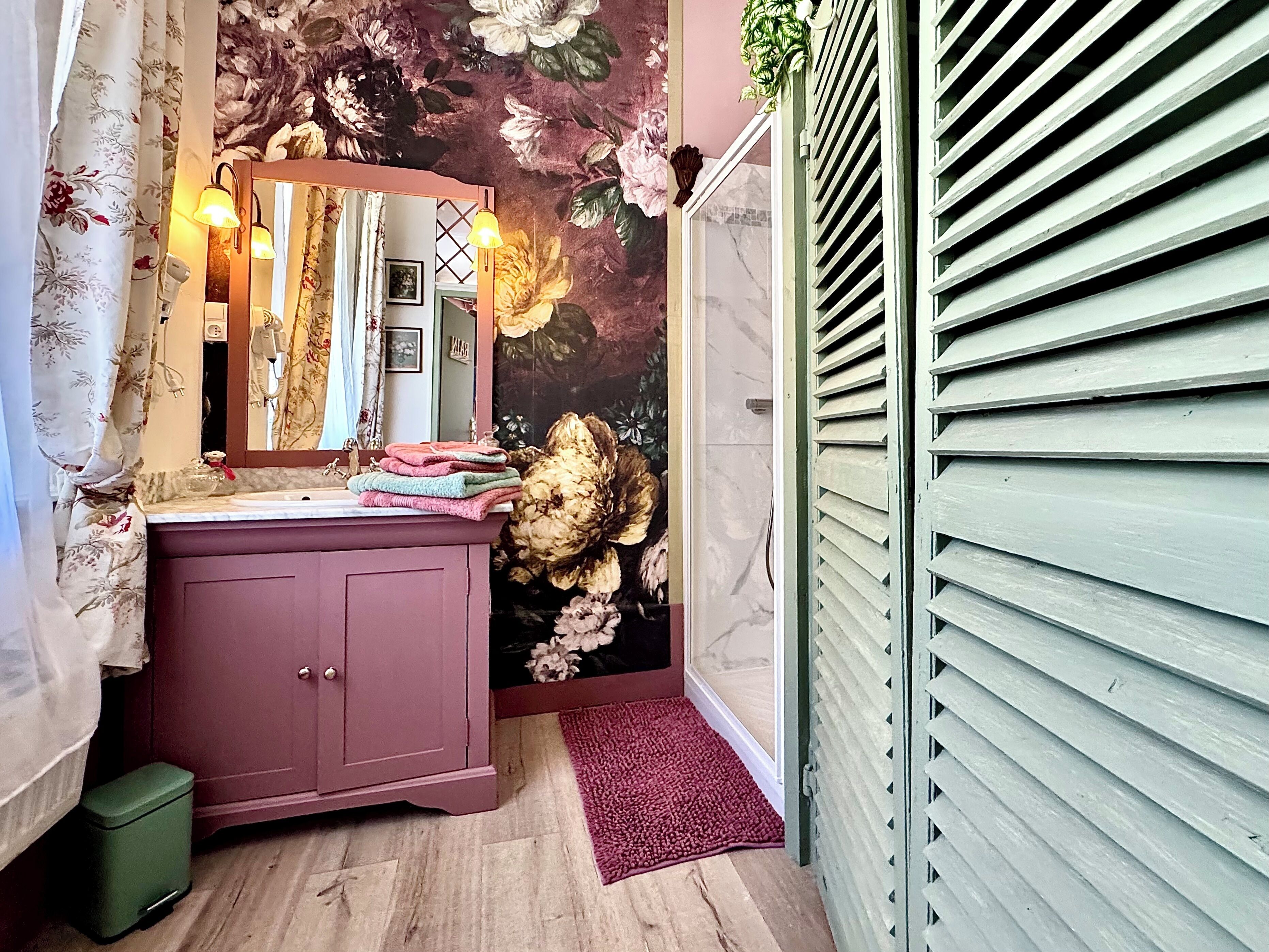 Ein Badezimmer mit Waschtisch, Spiegel und Blumenwallpaper.
