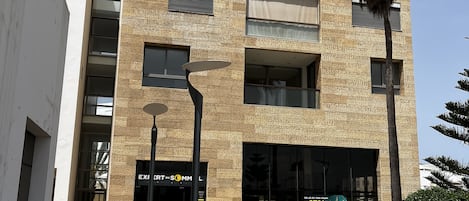 A modern building with a brick facade, large windows, and a storefront with a sign.