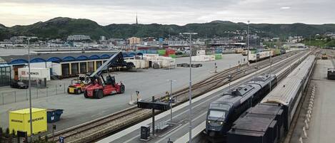 A railway station with multiple tracks, a freight train, and a forklift.