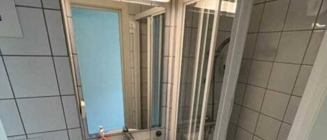 Un baño pequeño con lavamanos, espejo y ducha.