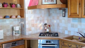 Une cuisine avec des meubles en bois, une cuisinière à gaz, un lave-vaisselle et une machine à café.