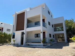 Un edificio moderno de varios pisos con balcones, una escalera y un camino de grava.