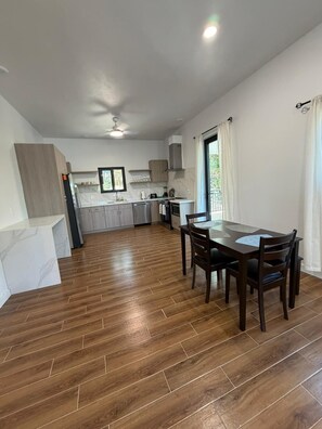 Une cuisine moderne avec un coin repas, un plancher en bois et une vue sur l’extérieur.