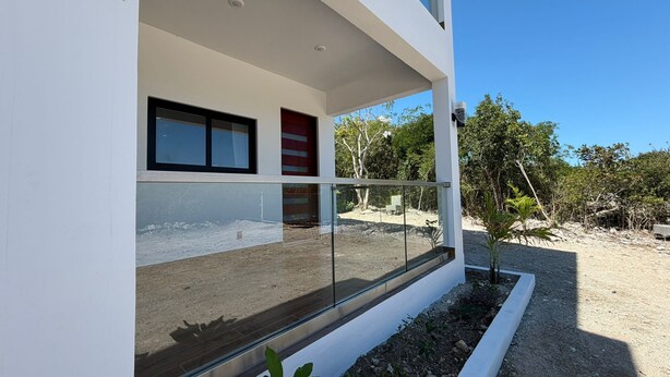 Ein modernes Gebäude mit großen Fenstern, einem Balkon und Blick auf die umliegende Landschaft.