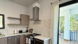 Eine moderne Küche mit Geschirrspüler, Backofen und Mikrowelle, Holzschränken und Blick auf einen Balkon.