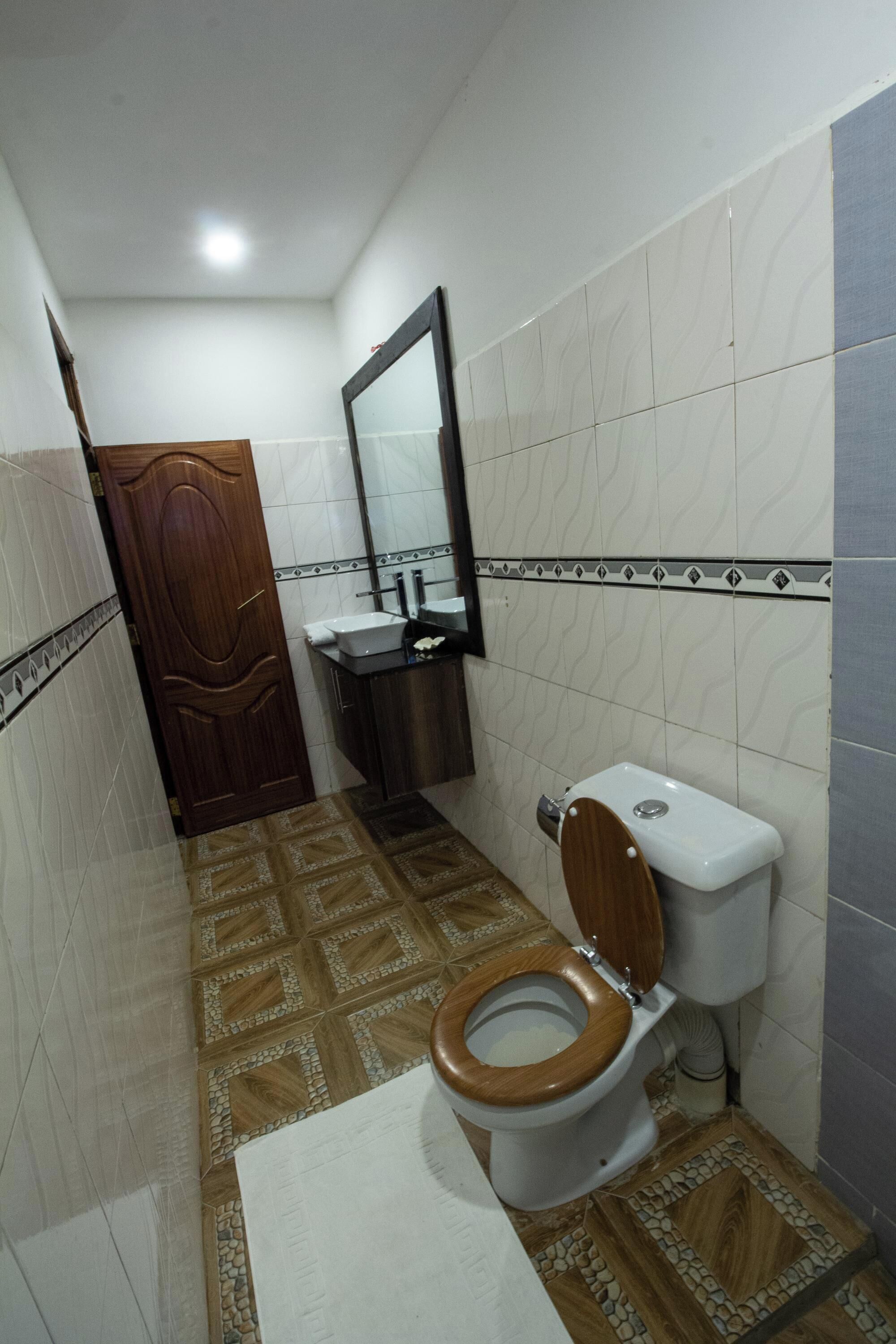 Een badkamer met een houten toilet, een wastafel en een spiegel.